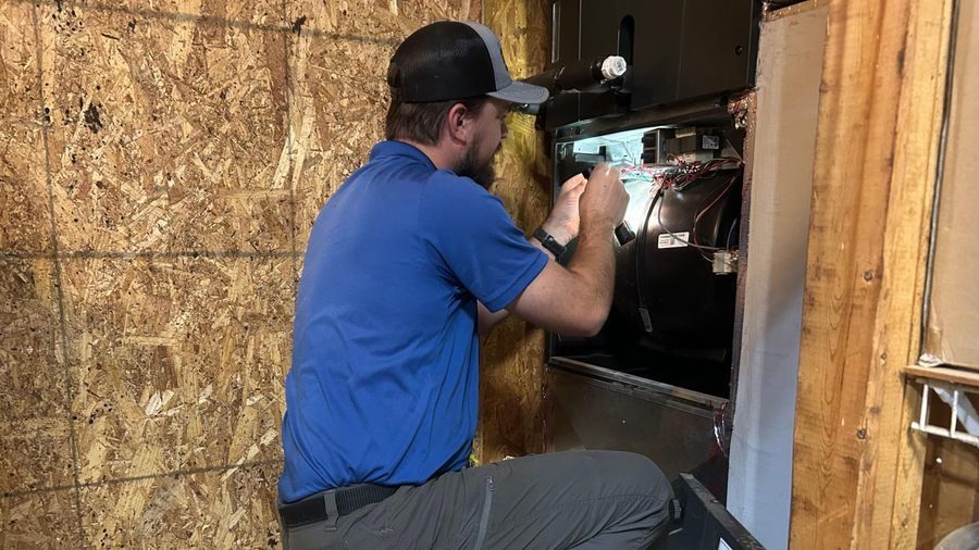 ZAP tech kneeling to repair heating system.